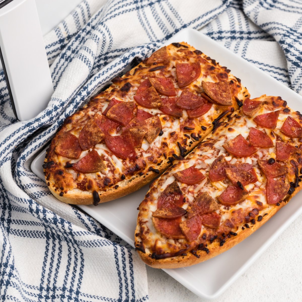 french bread pizza made in the air fryer and served on a white plate.