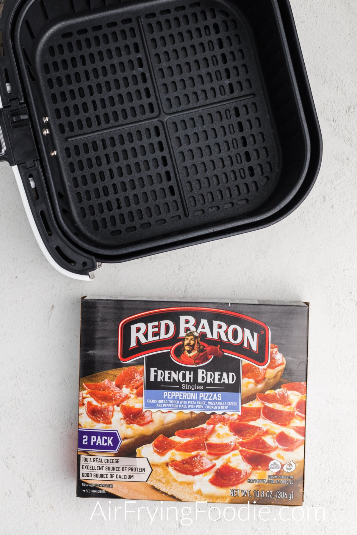 Air fryer basket and frozen french bread pizzas in a box. 