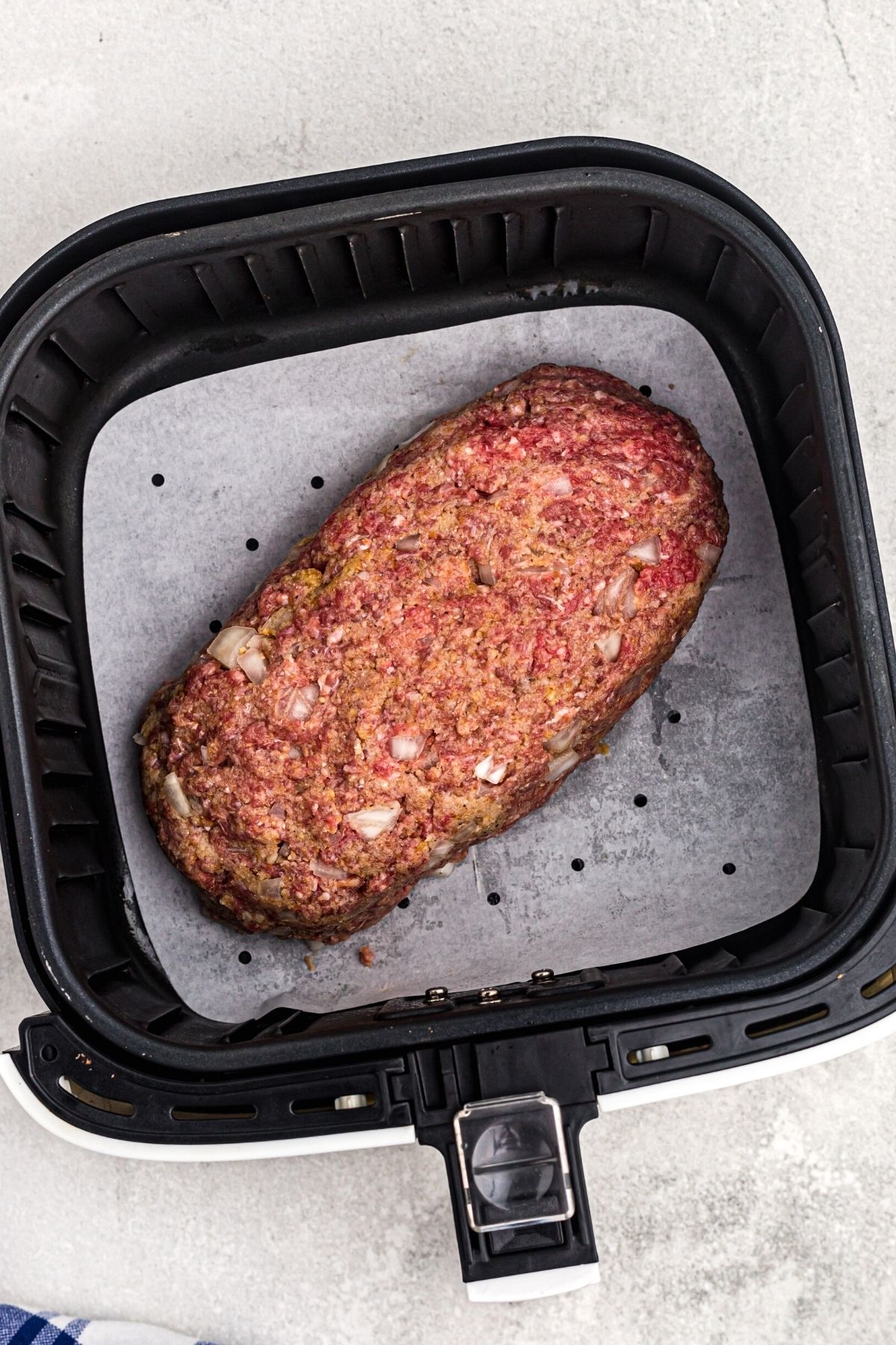Meat shaped into a loaf in the air fryer basket before being cooked