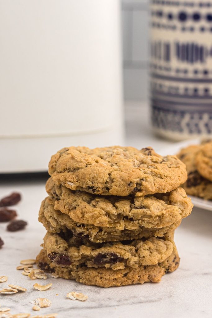 Golden oatmeal raisin cookies stacked in front of the air fryer