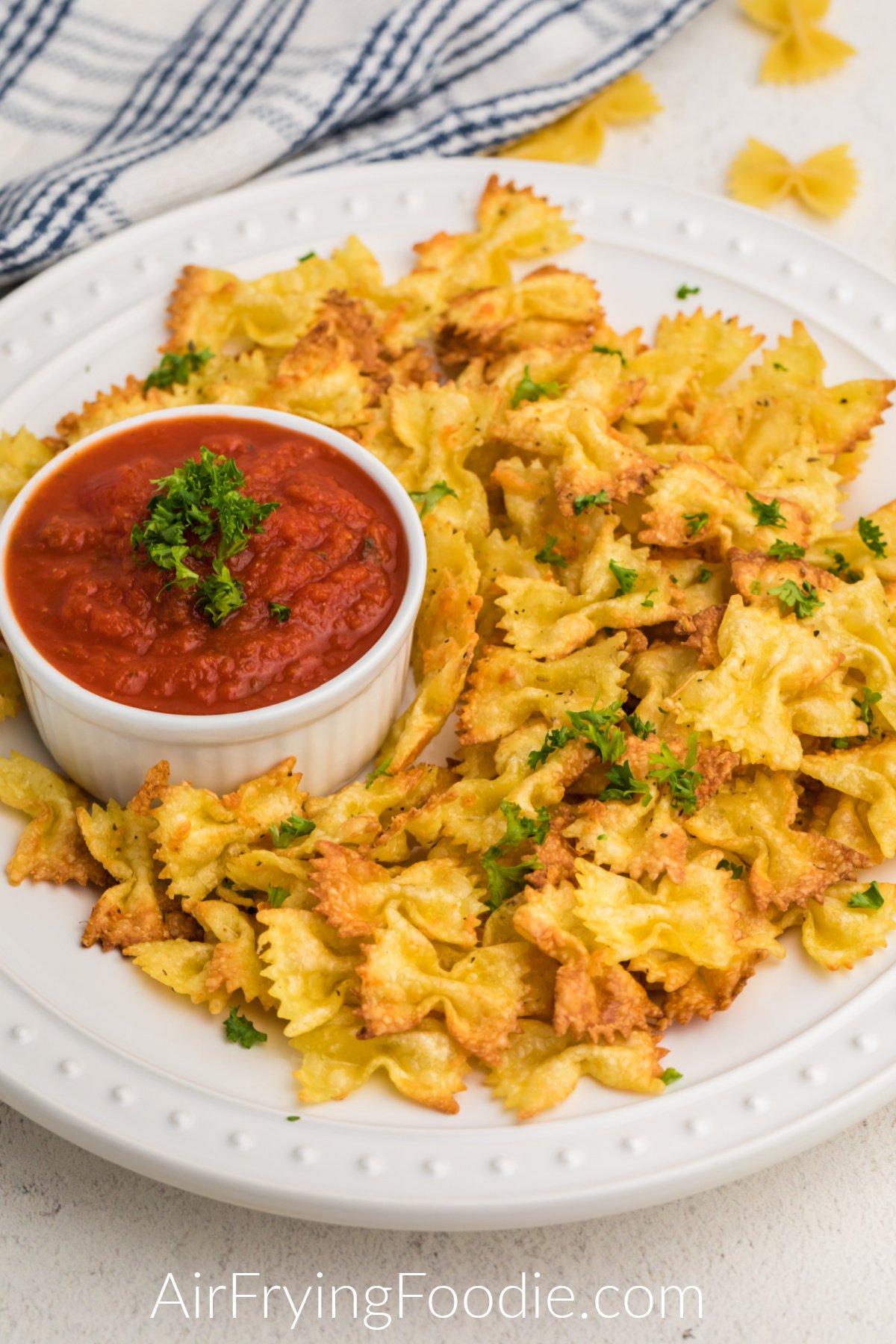 Fried Pasta Chips in the air fryer on a white plate served with marinara sauce. 