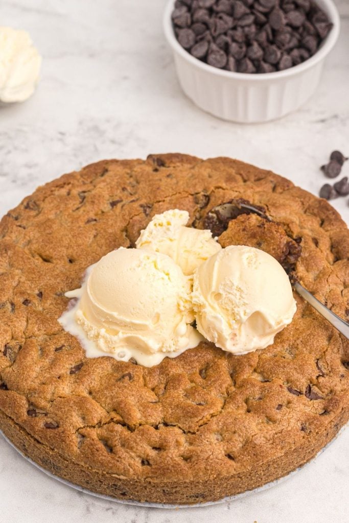Golden chocolate chip cookie with ice cream and a spoon scoop