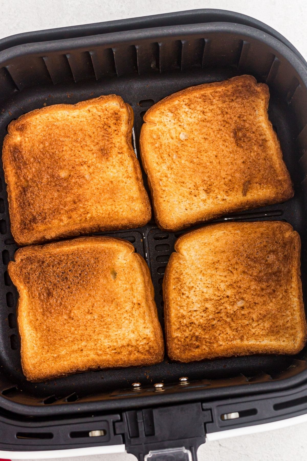 Four slices of golden toast after being cooked in the air fryer basket