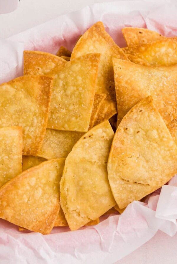 Golden crispy tortilla chips stacked in a basket.