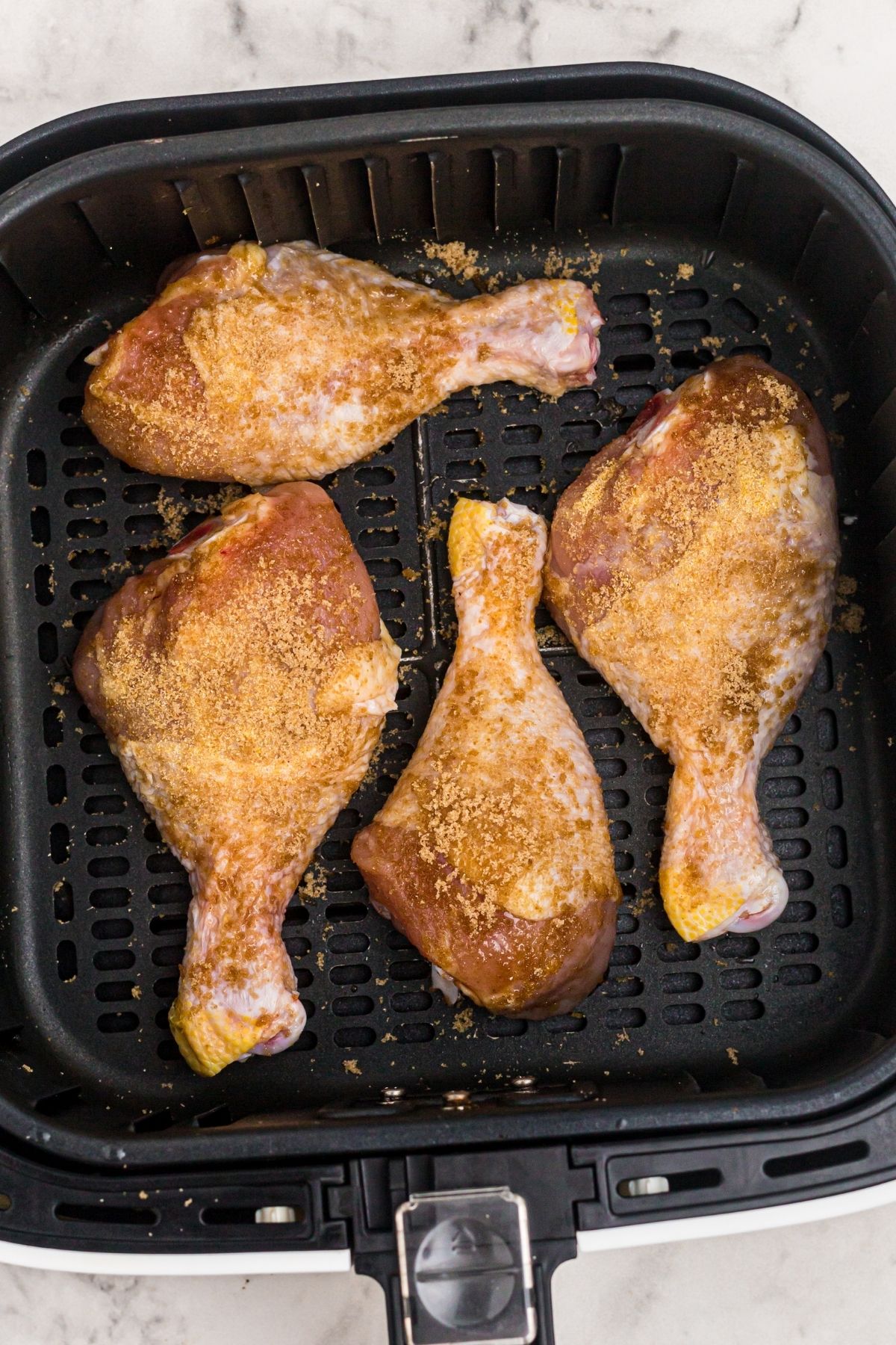 Coated chicken with seasonings in the air fryer basket before being cooked
