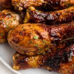 Juicy BBQ coated chicken on a white plate garnished with parsley flakes