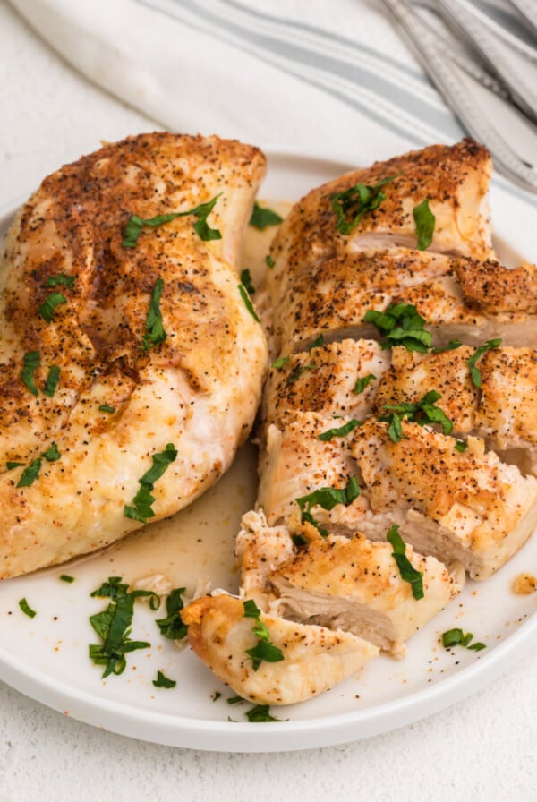 Overhead shot of seasoned chicken breasts made in the air fryer, served on a white plate.