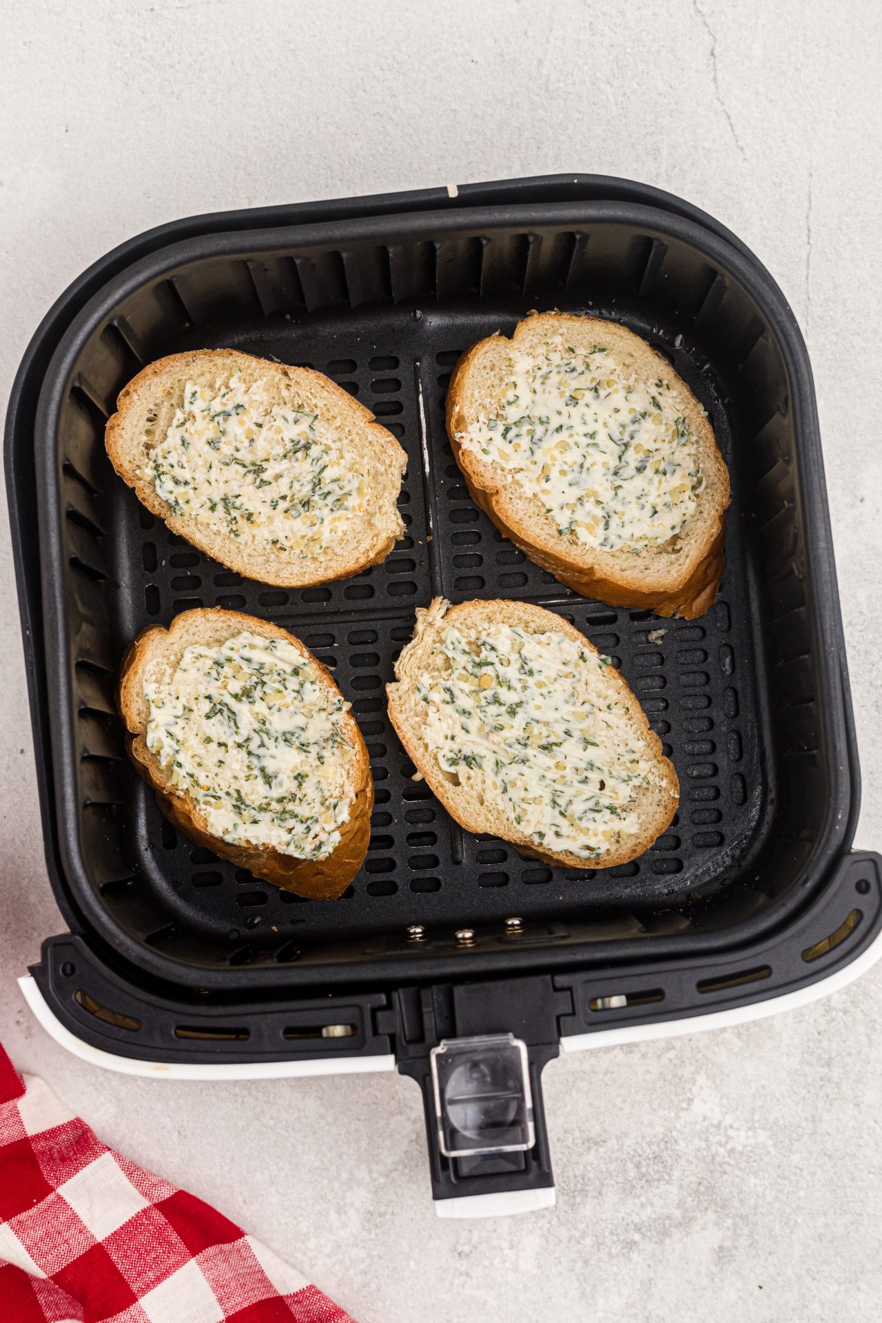 slices of bread with garlic butter spread on top in an air fryer basket