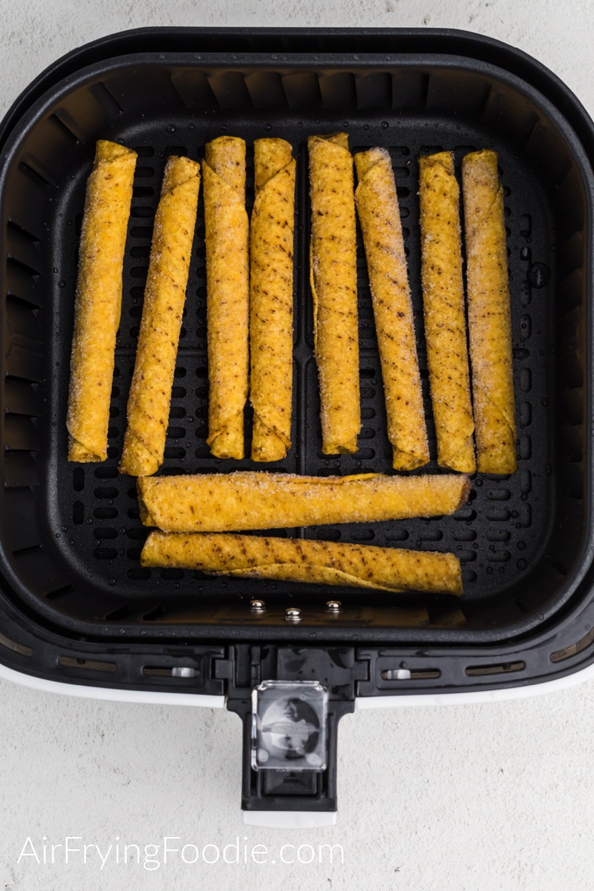 frozen taquitos in the air fryer basket in a single layer.