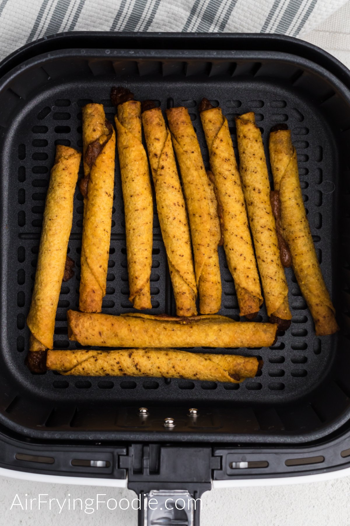 Cooked taquitos in the basket of the air fryer