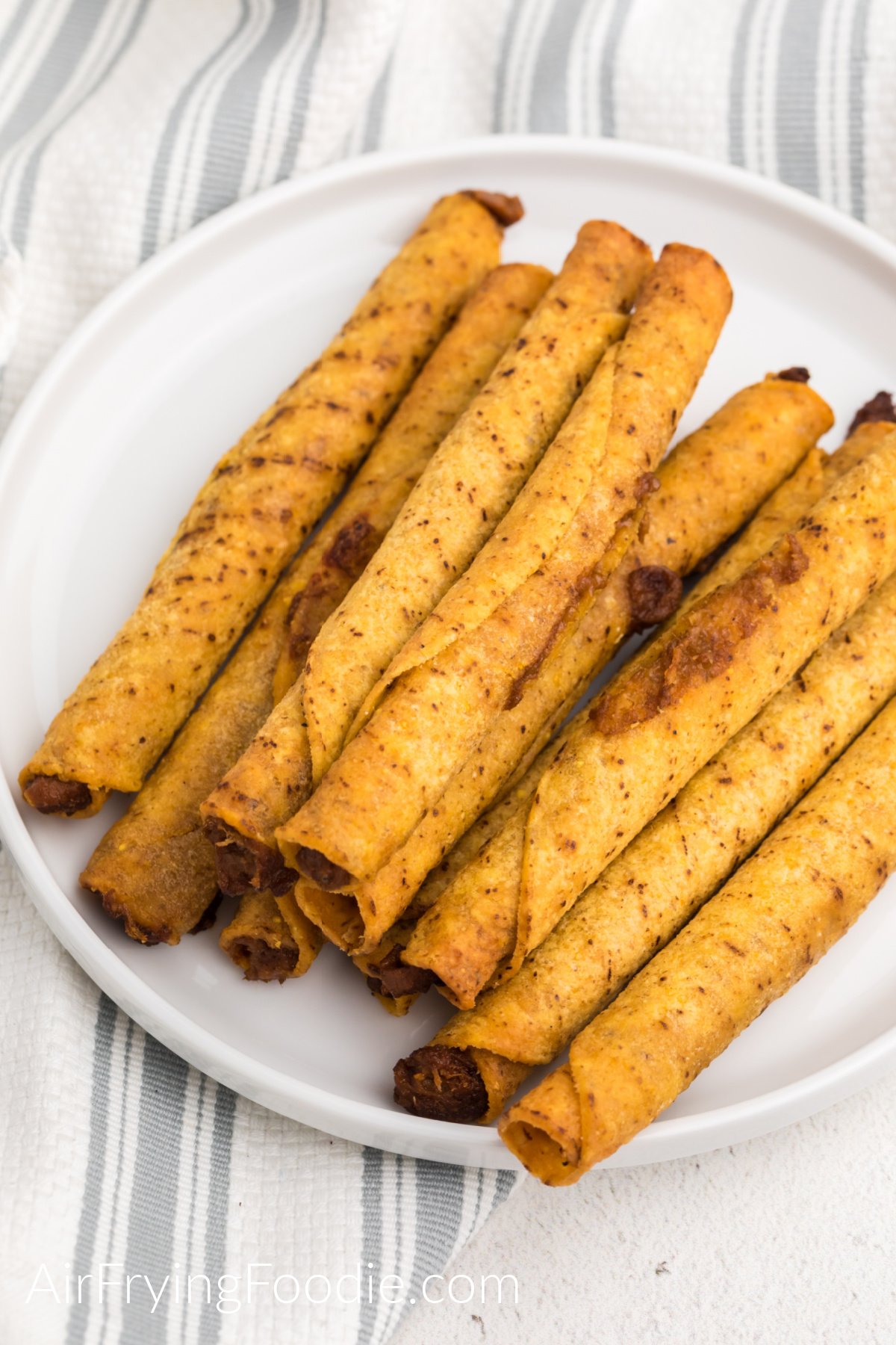Cooked taquitos on a white plate and ready to serve. 