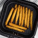 fully cooked taquitos in the air fryer basket in a single layer, ready to be removed and served.