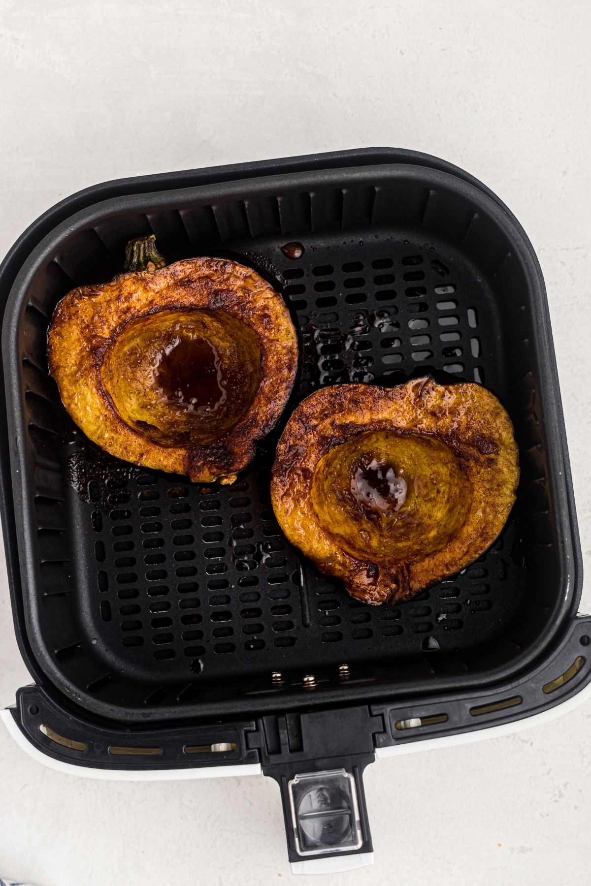 Golden brown cooked acorn squash in the air fryer basket.