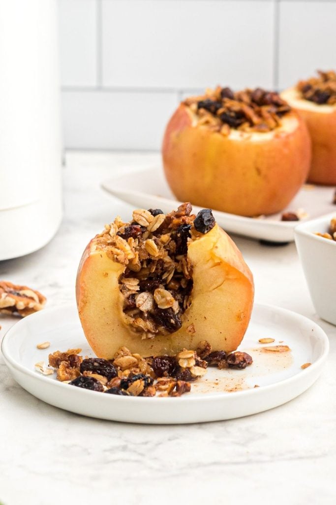 Golden baked apple cut open showing filling of oats, raisin, and nut mixture. 