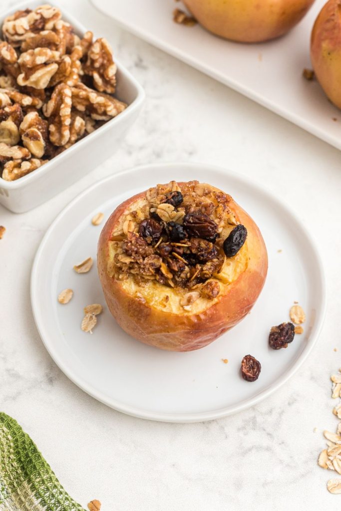 Golden apple baked and stuffed with oat mixture on a white plate
