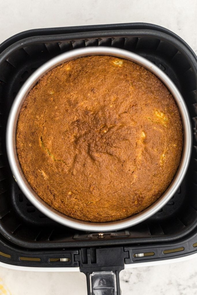 Golden cooked banana bread in a cake pan in the air fryer basket. 