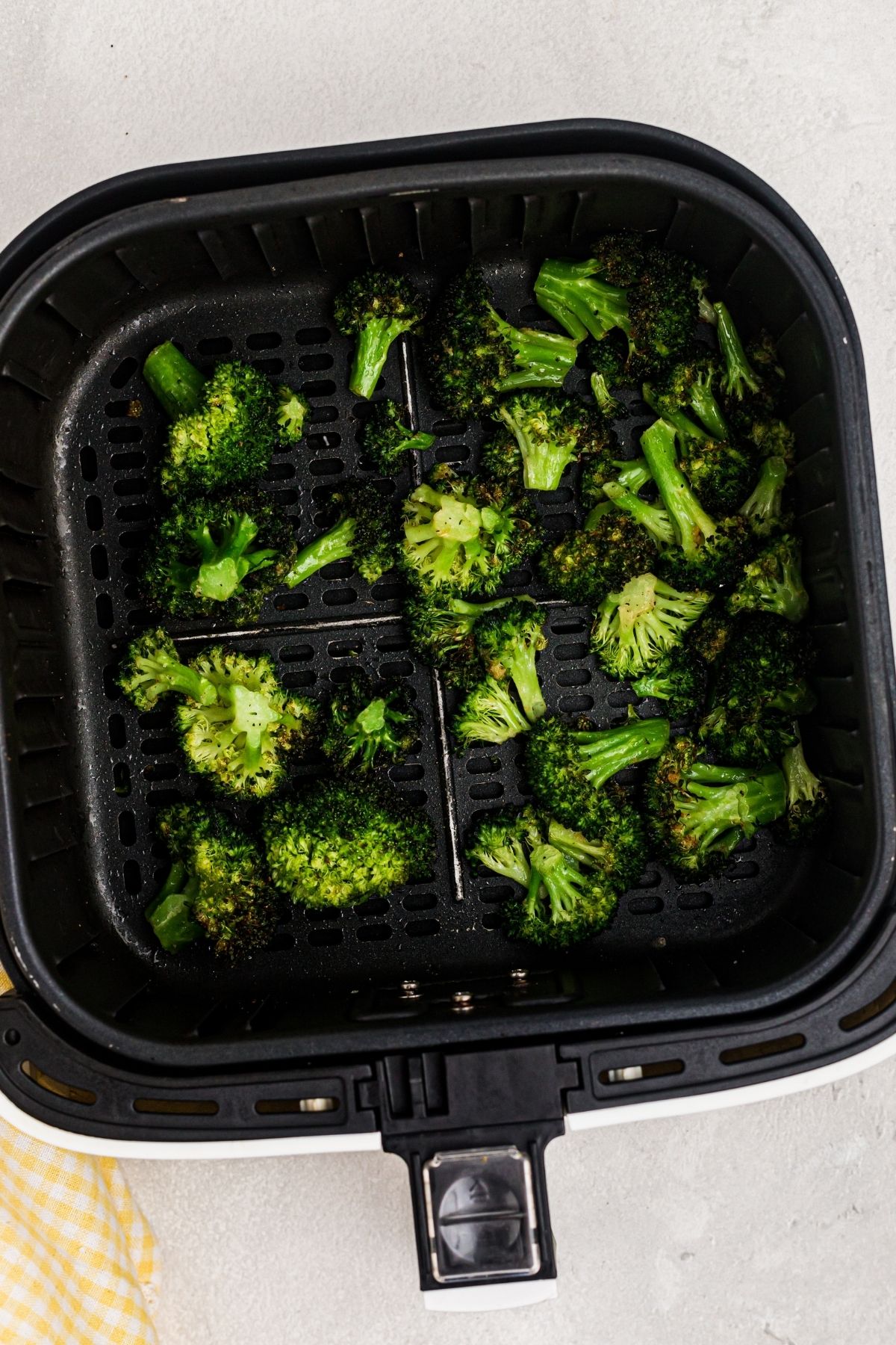 Air fried broccoli in the air fryer basket after being cooked