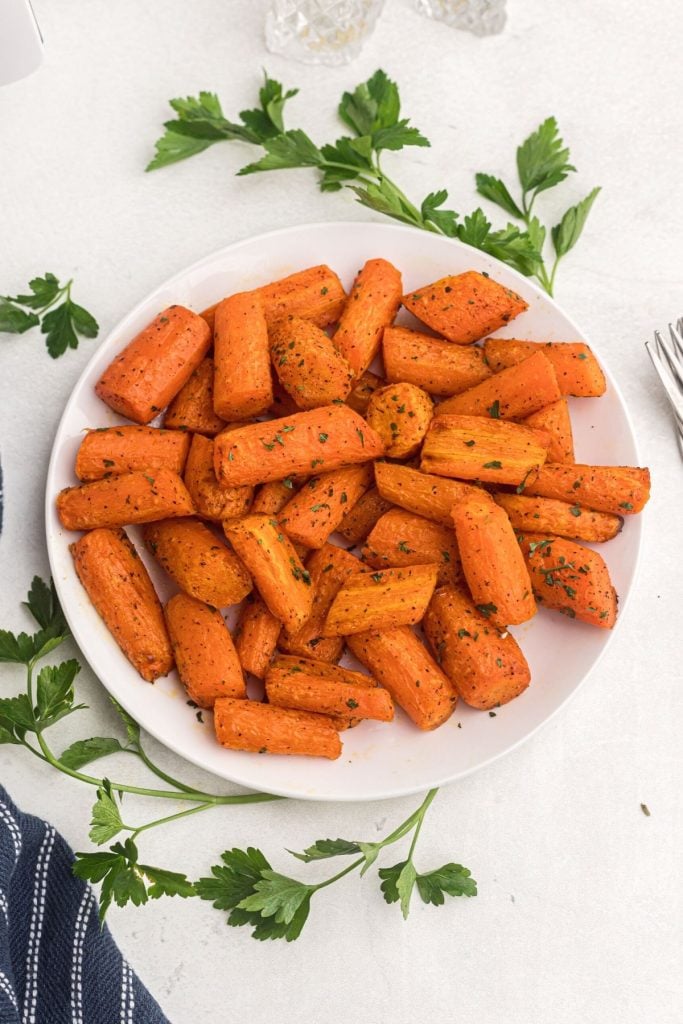 Juicy orange carrots garnished with parsley after being cooked in air fryer. 