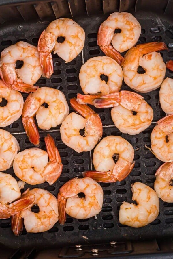 Juicy orange shrimp in the air fryer basket after being cooked from frozen.