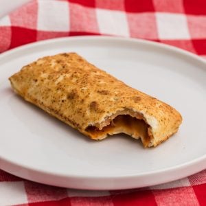 Hot pocket on a white plate with a bite taken out of it.