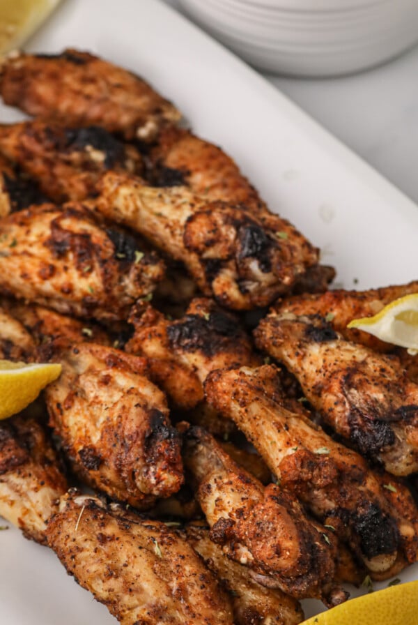 Air Fried Lemon Pepper Wings on a white plate with lemon slices.