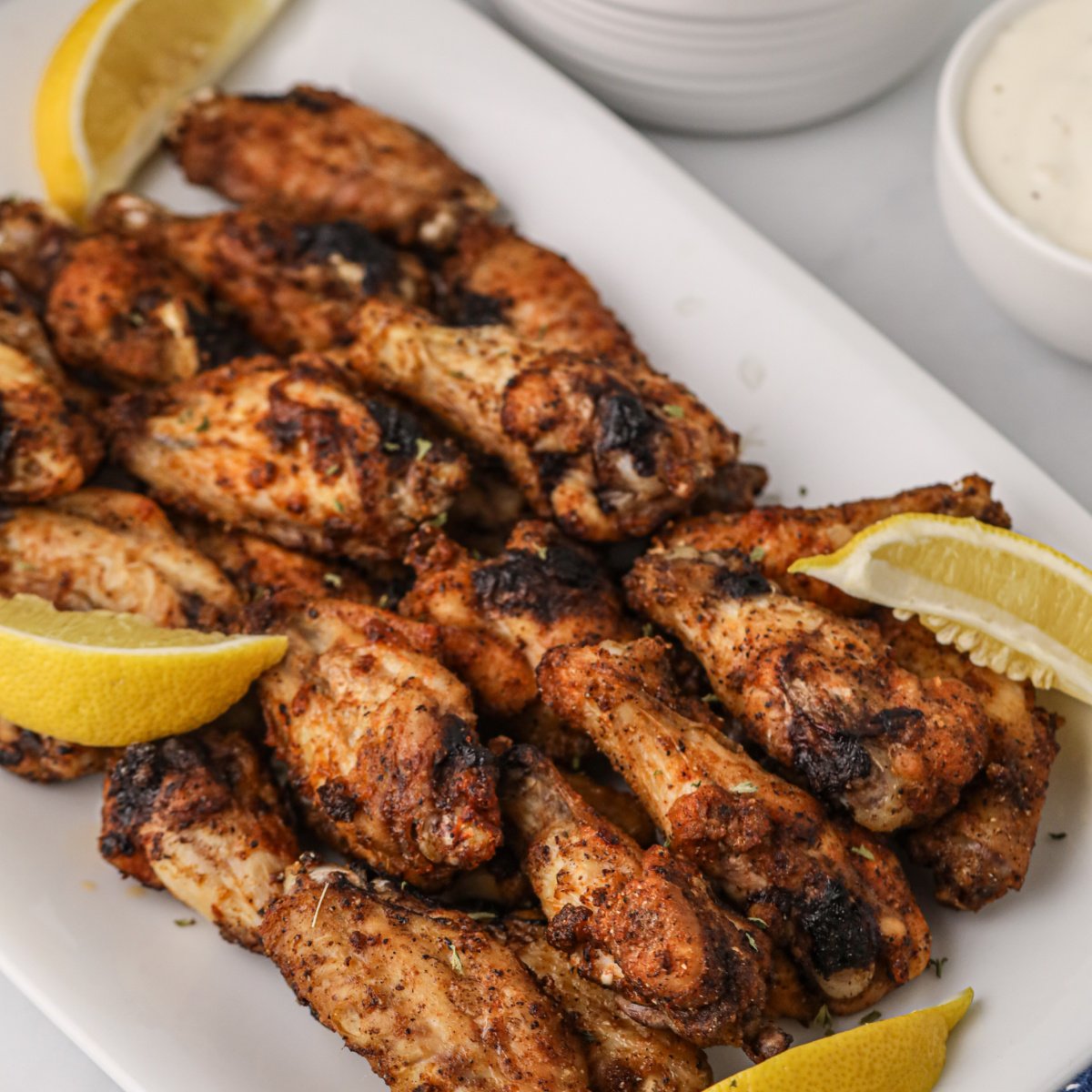 Air Fried Lemon Pepper Wings on a white plate with lemon slices.