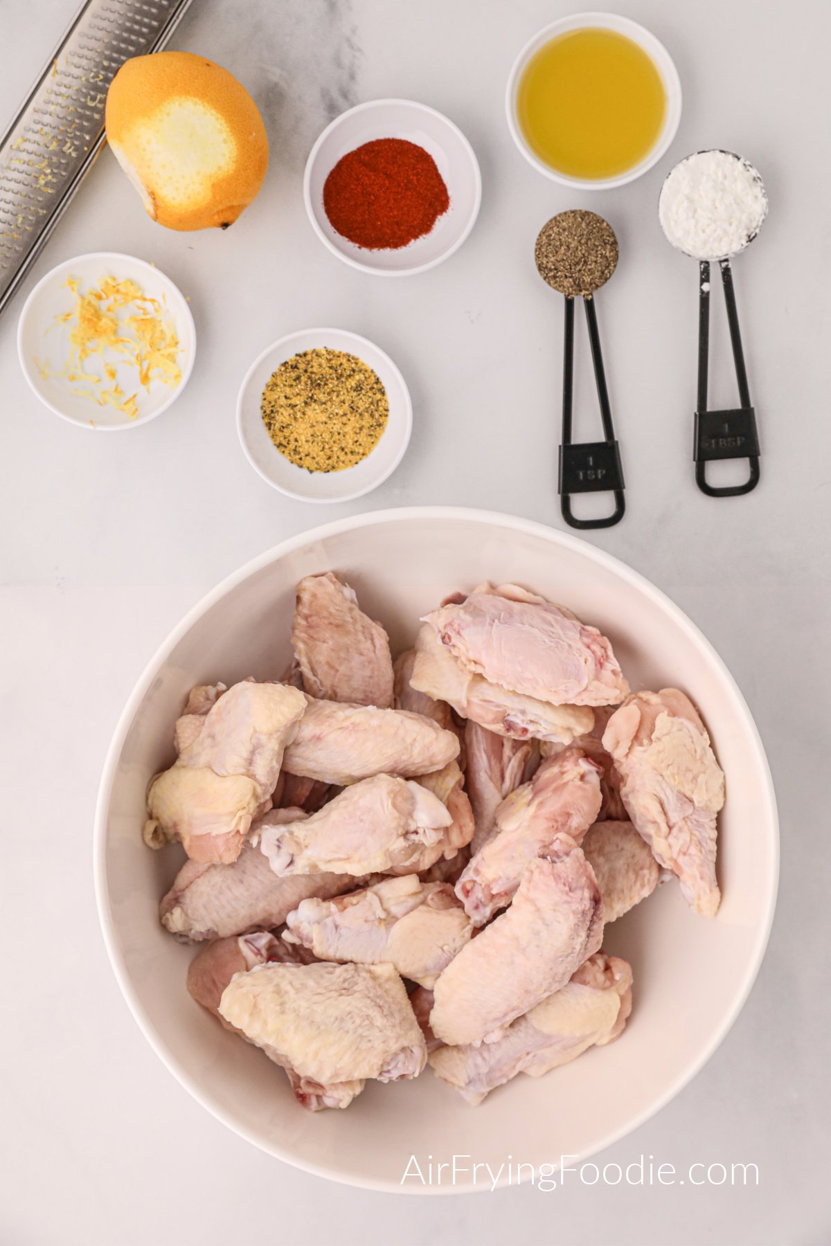 White countertop with ingredients needed to make lemon pepper wings in the air fryer. 