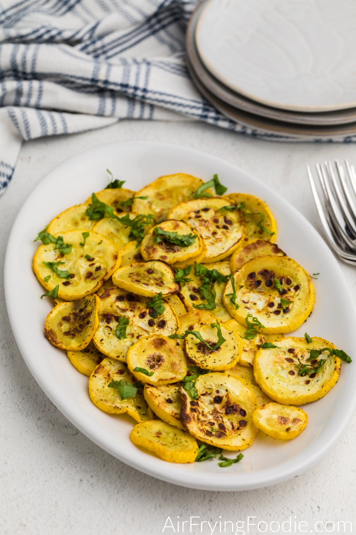 Air fried squash on a white plate topped with fresh parsley and ready to serve.