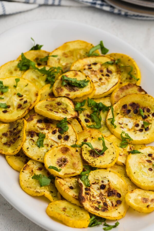 Yellow squash cooked in the air fryer on a white plate and ready to serve.