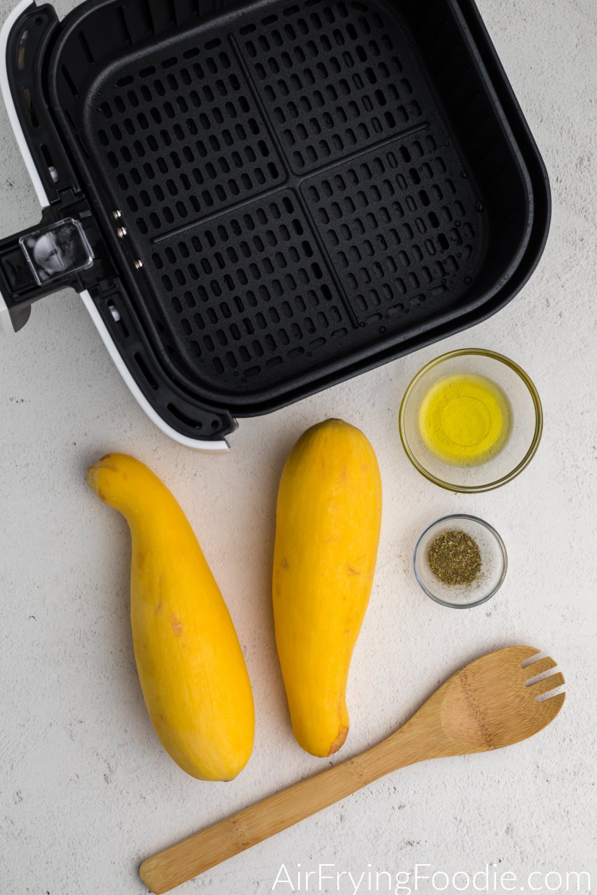 air fryer basket and ingredients needed to make sliced squash in the air fryer.