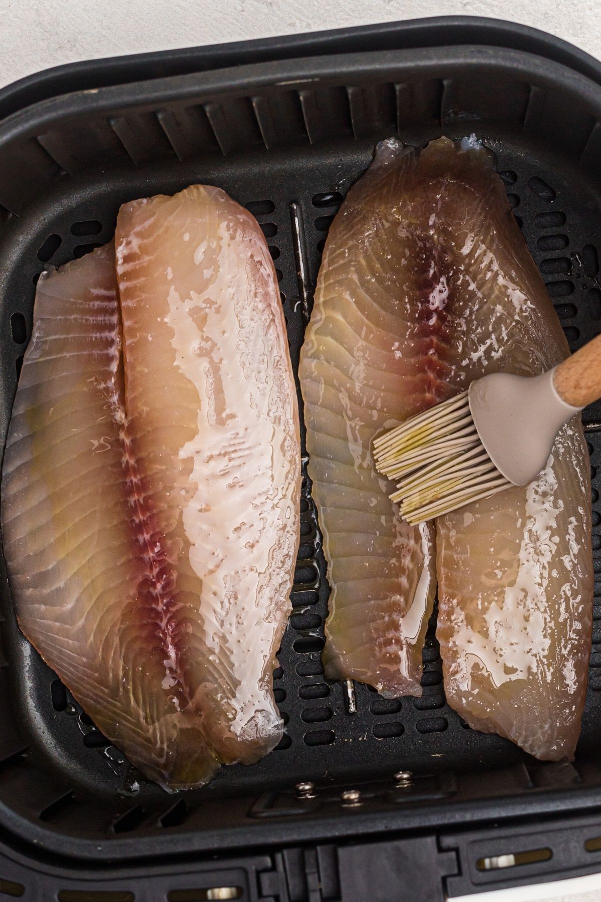 brushing oil onto fish filets before seasoning and cooking