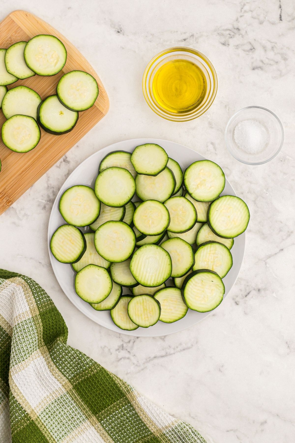 zucchini cut into slices on a wooden cutting board with olive oil and seasonings. 