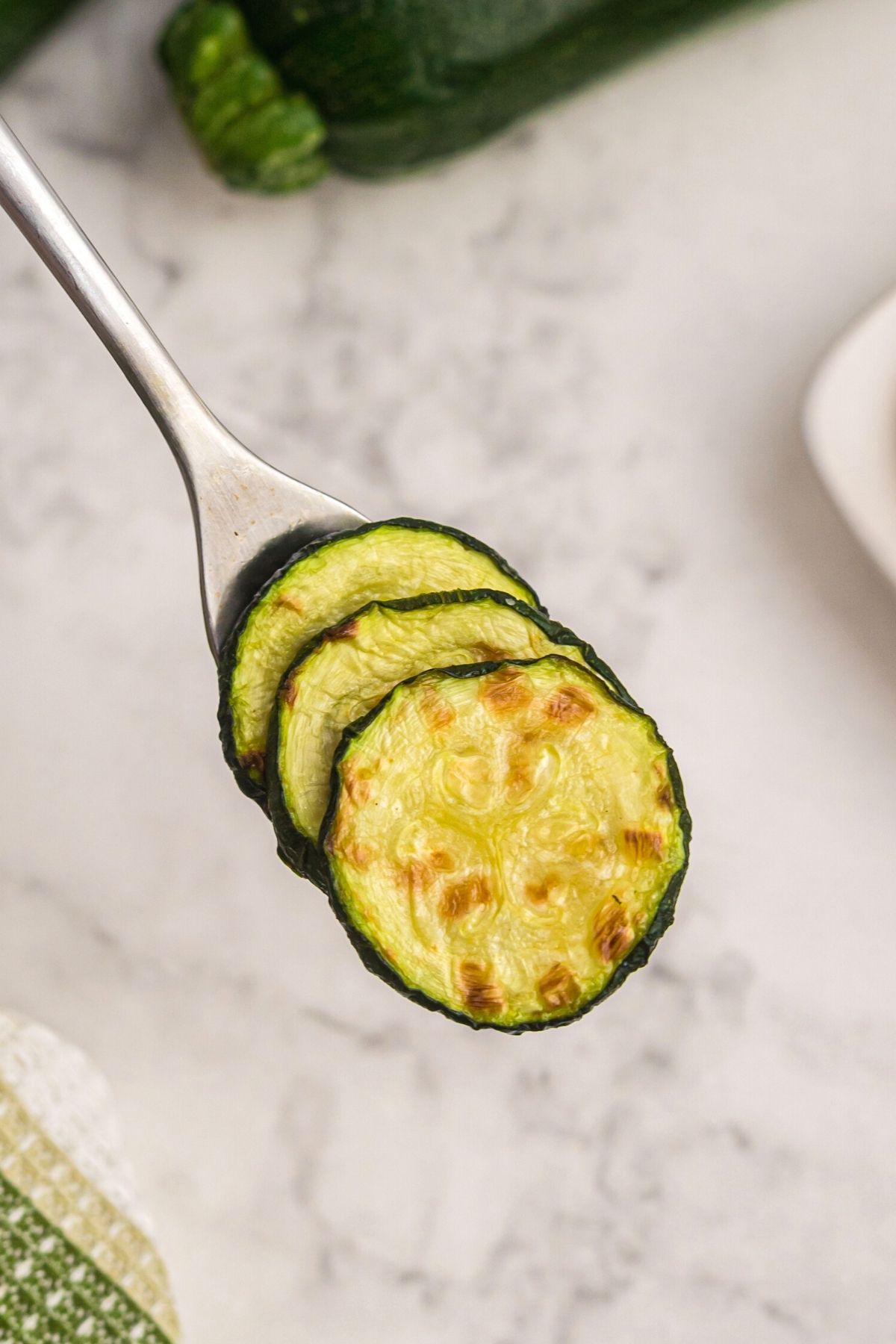 Fork serving zucchini slices after air frying. 