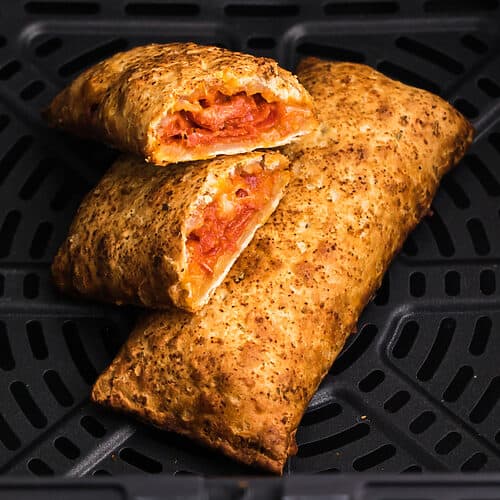 Close up of hot pockets in air fryer with one sliced in half and ready to eat.