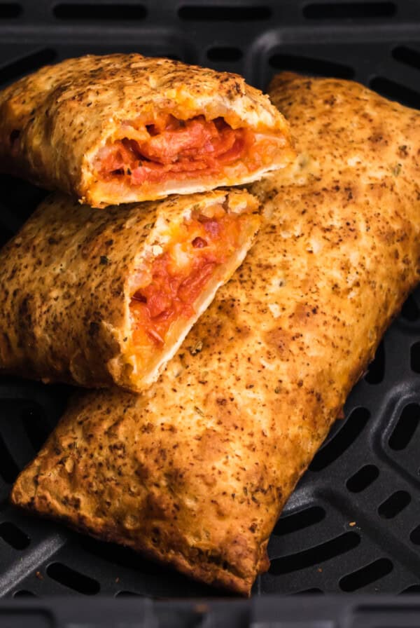 Close up of hot pockets in air fryer with one sliced in half and ready to eat.