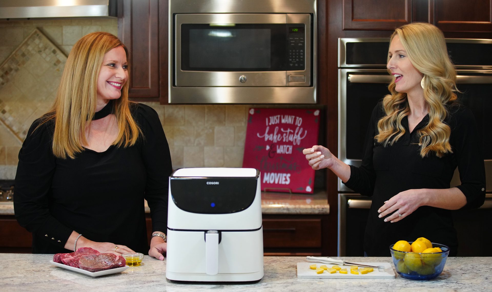 Jen and Rebecca talking in the kitchen about recipes, with a Cosori air fryer on the kitchen island. 
