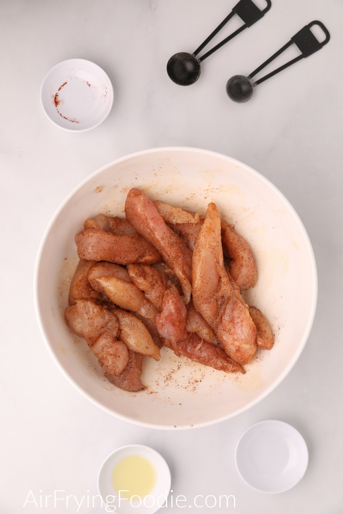 Seasoned chicken tenders in a bowl ready to be cooked in the air fryer.