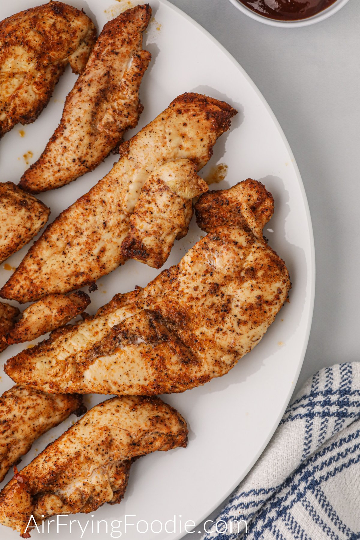 Fully cooked chicken tenders on the white plate and ready to eat. 