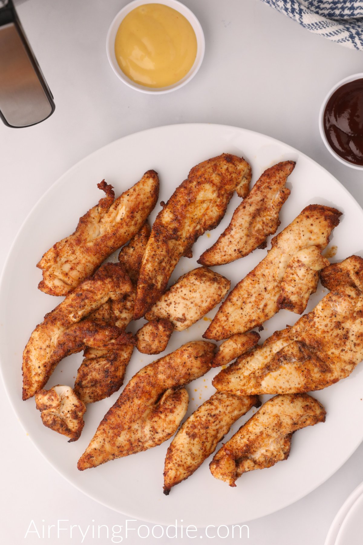 Grilled Chicken Tenders cooked and seasoned and served on a white plate. 