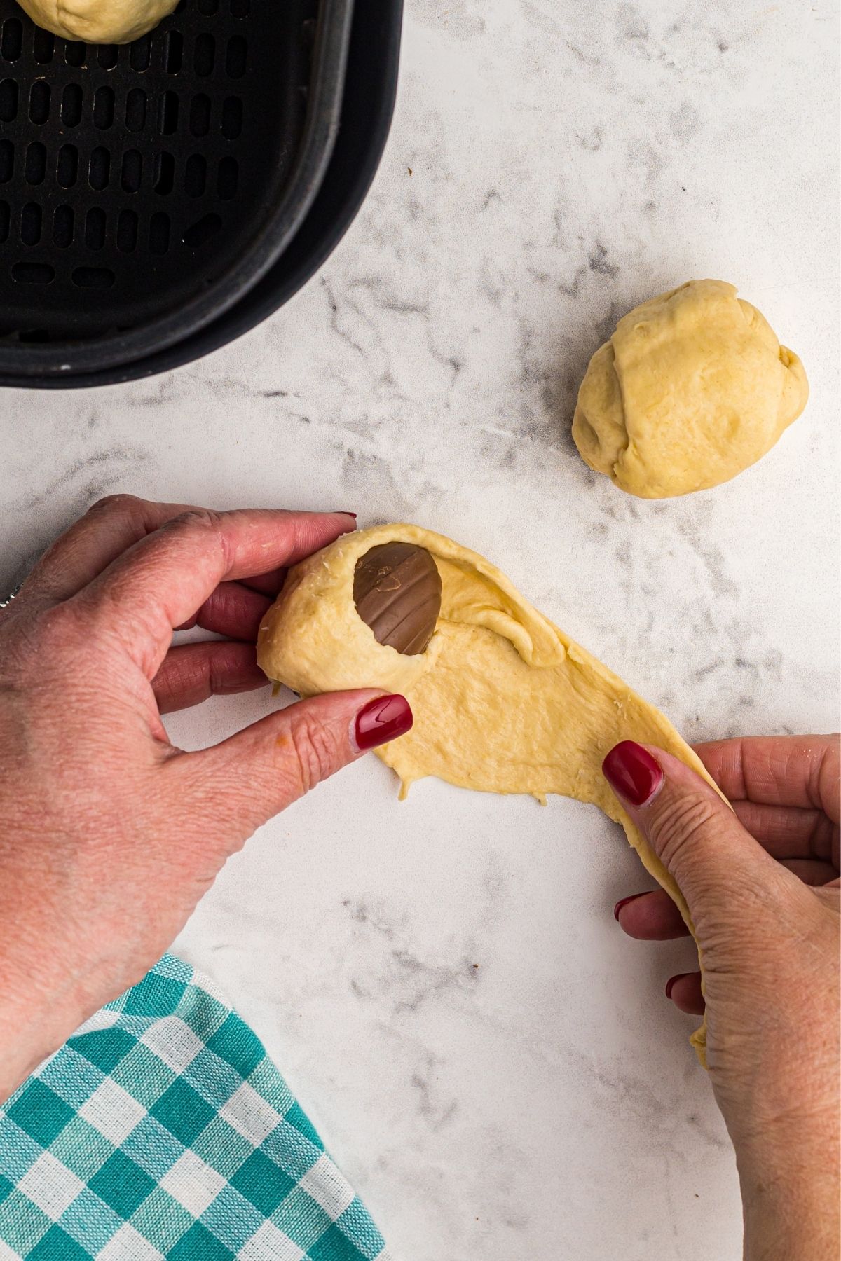 Wrapping eggs in crescent rolls before placing in air fryer basket.