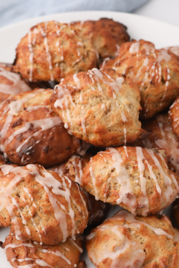 Plate full of air fryer apple fritters topped with a sweet glaze and served on a white plate.