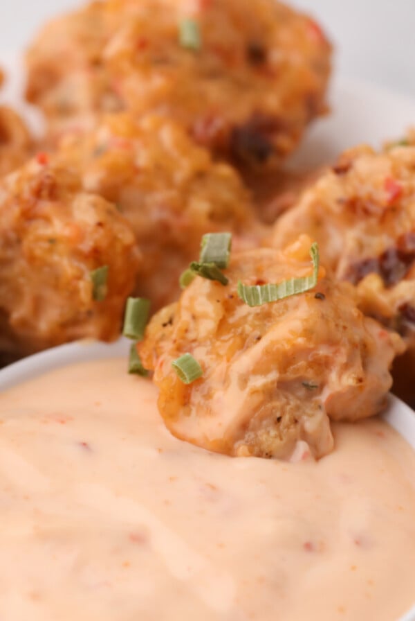 Air Fryer Bang Bang Shrimp in dipping sauce and on a white plate.