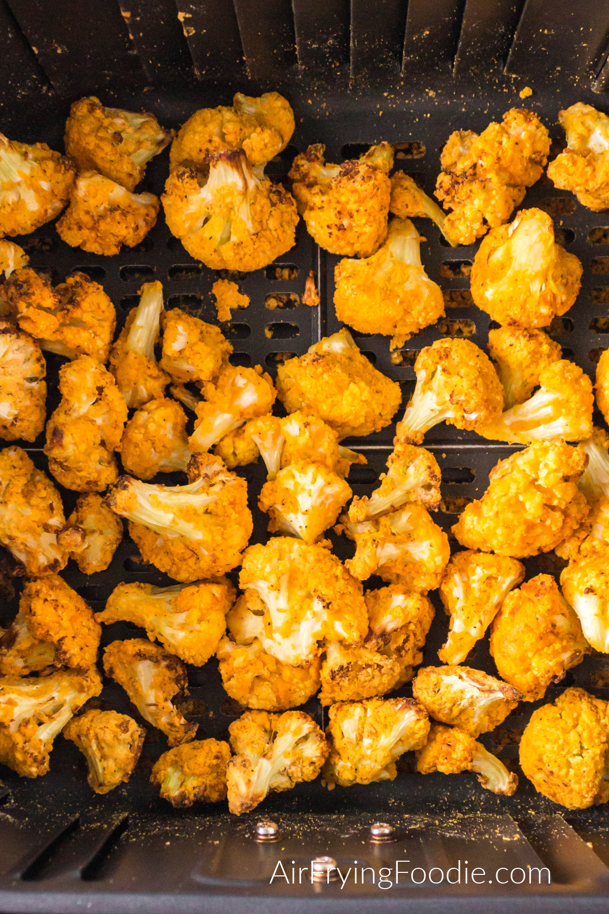 Air fried buffalo cauliflower bites in the basket of the air fryer.