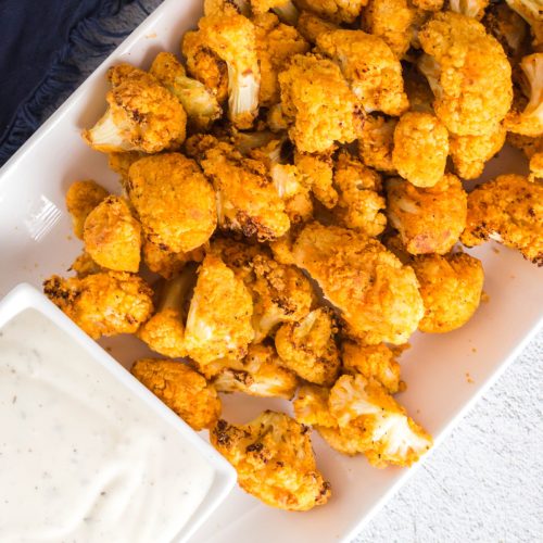 Plate of air fryer buffalo cauliflower with a side of dipping sauce.