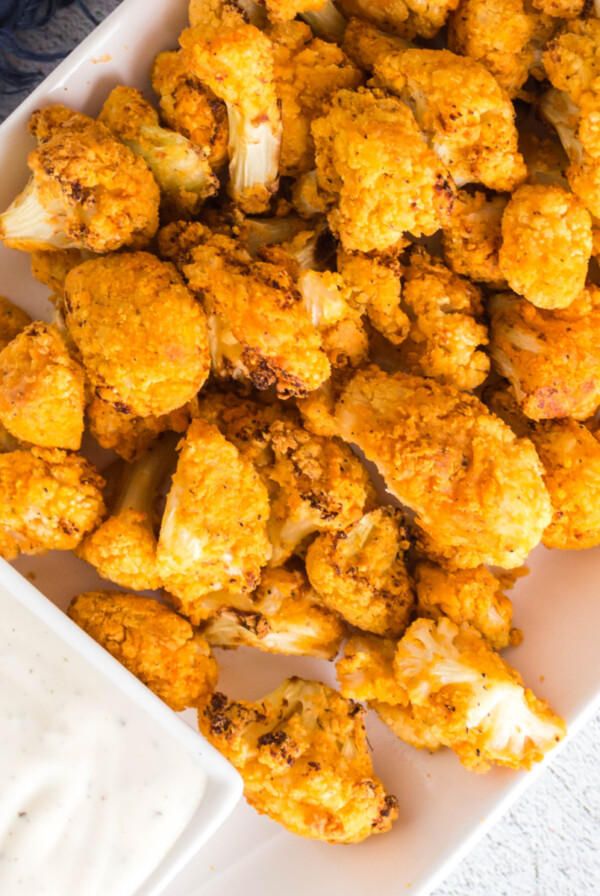 Plate of air fryer buffalo cauliflower with a side of dipping sauce.