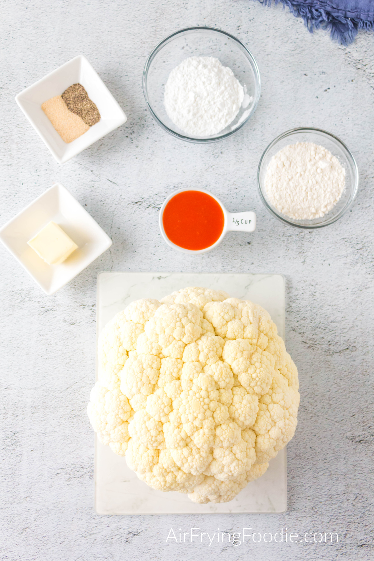 Ingredients needed to make buffalo cauliflower bites in the air fryer - set out on a table. 