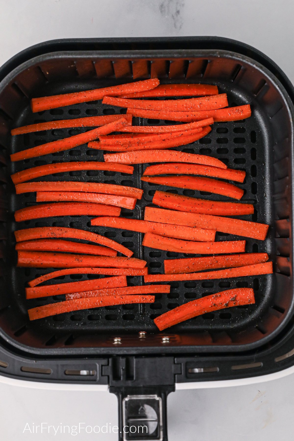 Carrot fries cut and placed in the air fryer basket.