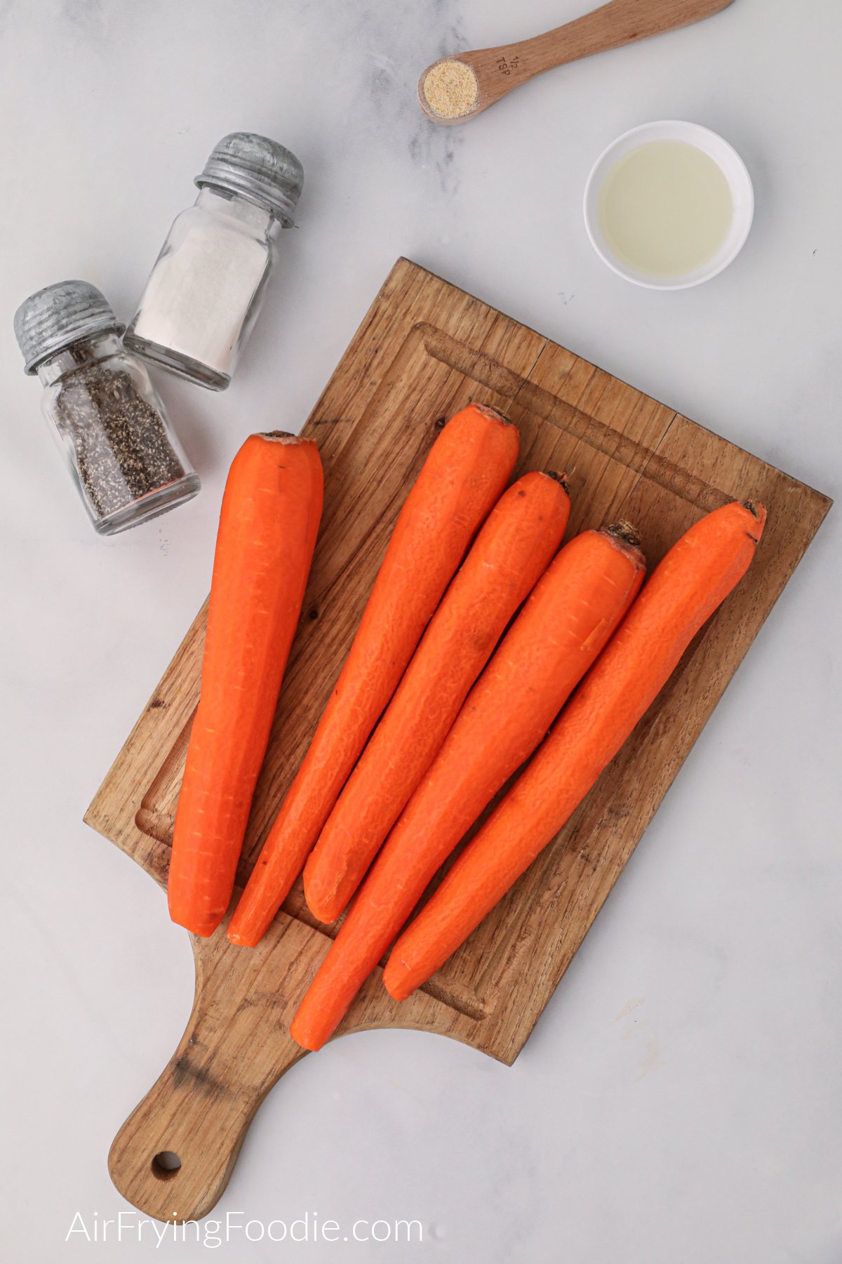 Ingredients on a white table and carrots on a cutting board. 