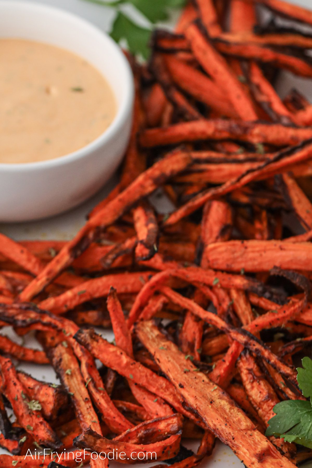 Air fried carrot fries on a plate with dipping sauce, ready to eat. 