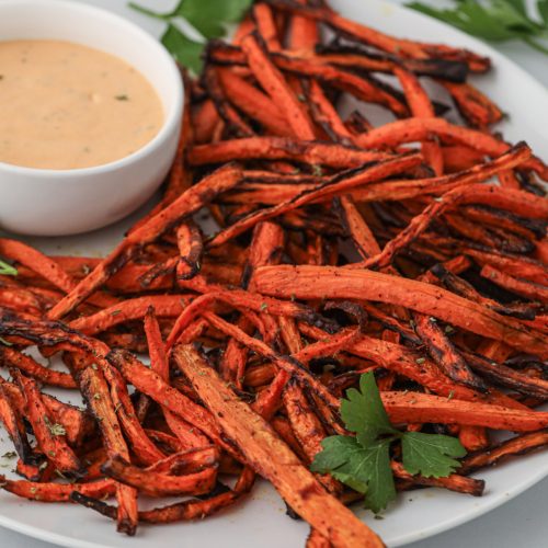 Carrot fries made in the air fryer and served on a plate with dipping sauce.